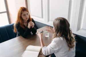 a woman sits with her therapist at table and discusses how a anxiety treatment program can help her