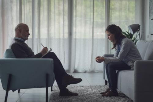 a patient sits on a couch across from their therapist who is sitting in a chair while in a depression treatment program