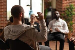 a guy raises his hand in in his boston IOP group therapy session
